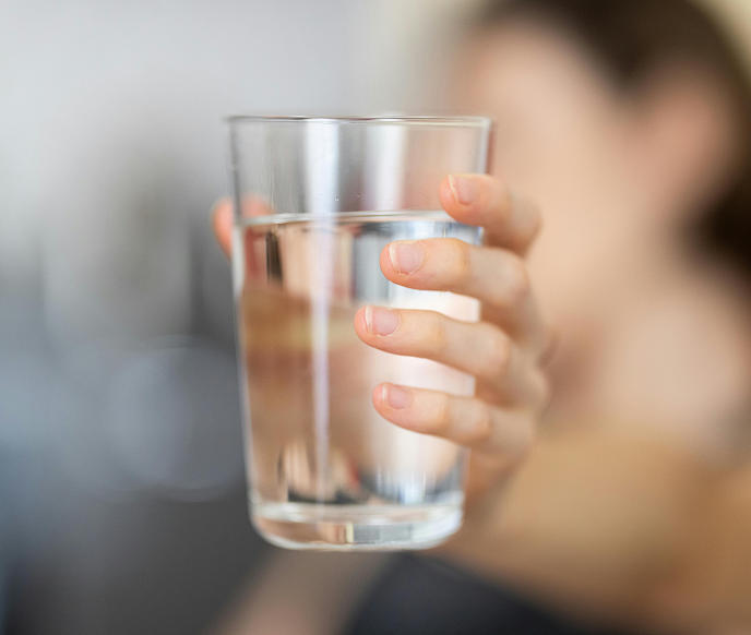 Someone holding up a glass of water with a blurry background